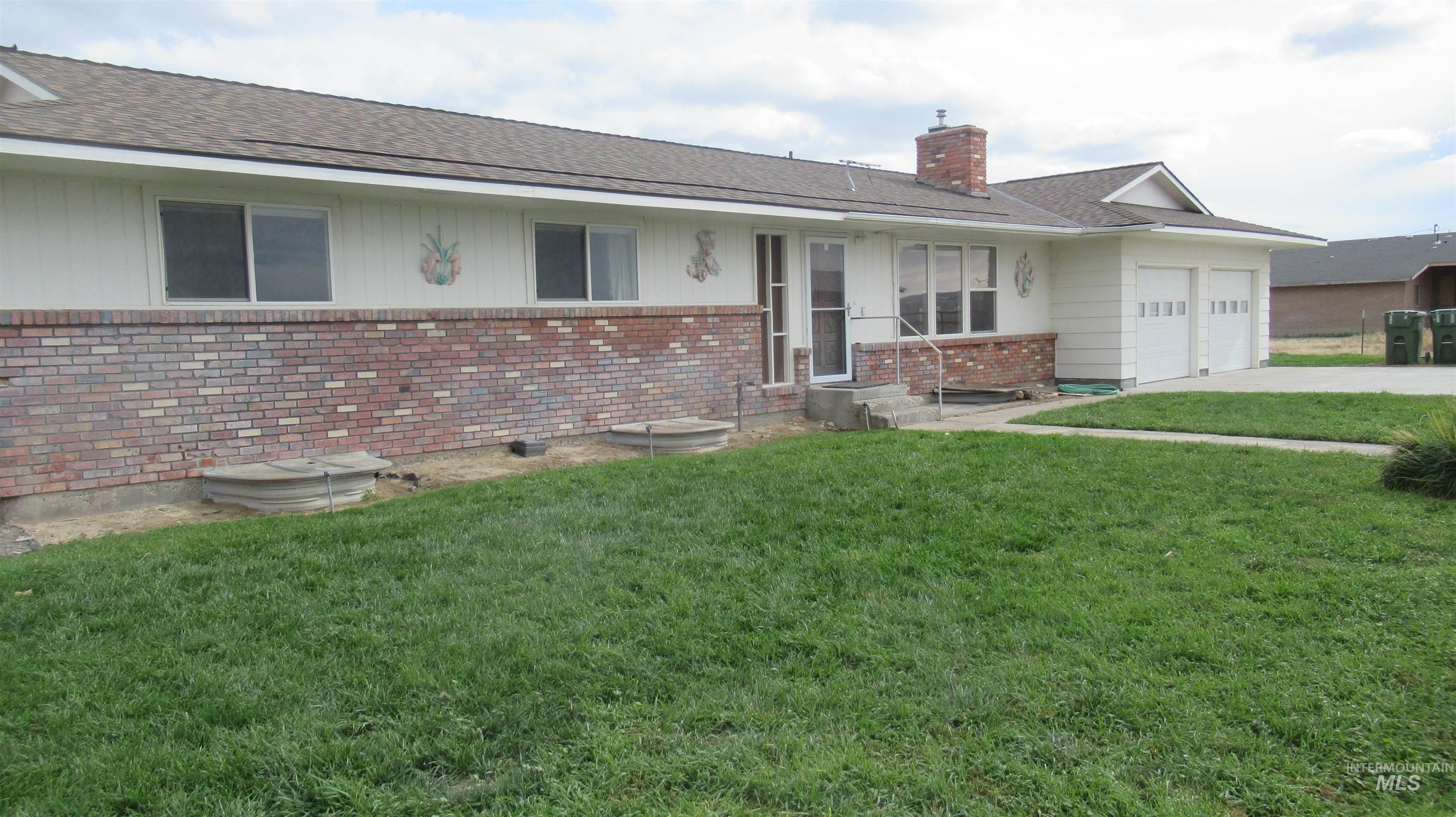 View of front of home featuring a front lawn, brick siding, a chimney, and roof with shingles