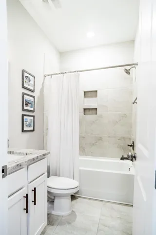 a bathroom with a granite countertop sink a toilet and shower