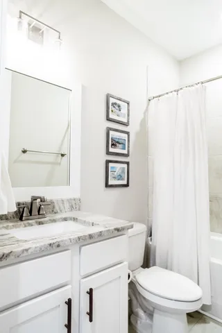 a bathroom with a granite countertop sink mirror vanity and toilet