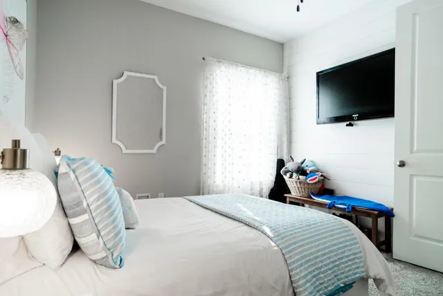 a bedroom with a bed and a flat tv screen on wall