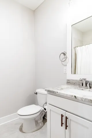 a bathroom with a granite countertop toilet sink and mirror