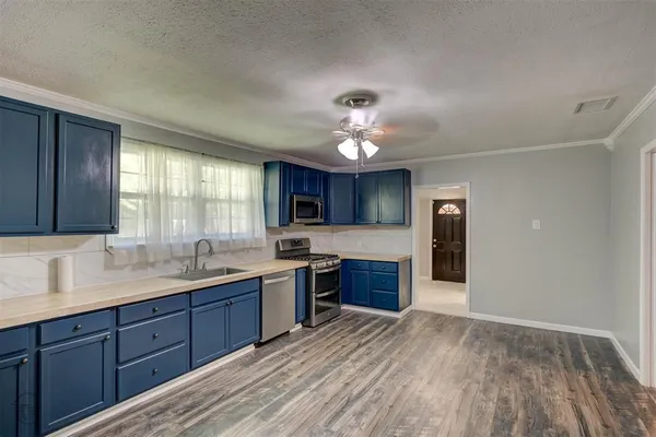 a large kitchen with stainless steel appliances granite countertop a refrigerator a sink dishwasher a stove and white countertops with wooden floor