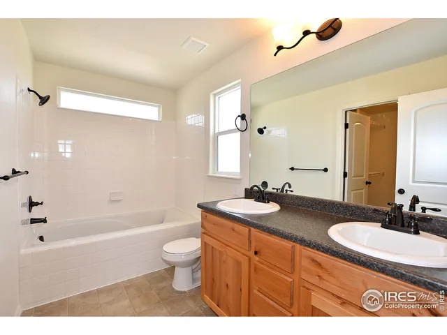 a bathroom with a granite countertop sink a toilet a mirror a bathtub and shower