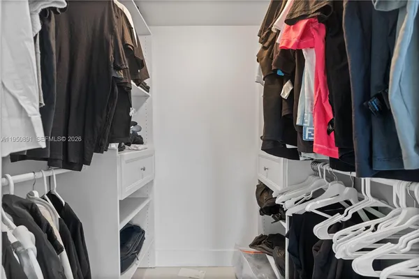 a view of walk in closet with clothes and shoes