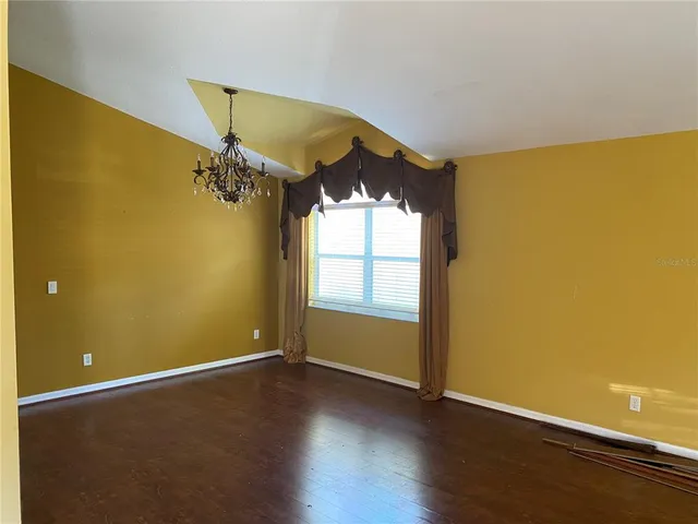 a view of a room with a chandelier fan and wooden floor