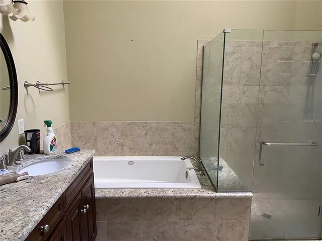 a bathroom with a granite countertop bathtub sink vanity and toilet