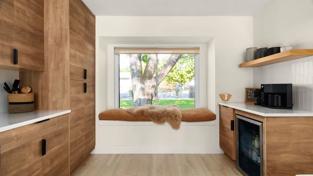 a living room with stainless steel appliances furniture a fireplace and a large window