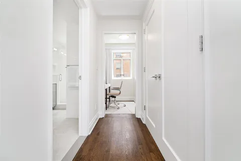 a view of a hallway with wooden floor and a bathroom