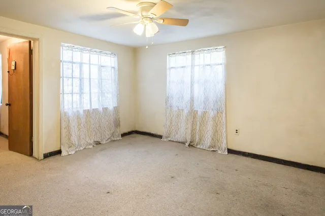 an empty room with windows and fan