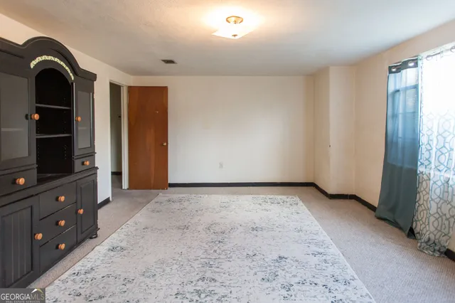 a view of an empty room and window with cabinet