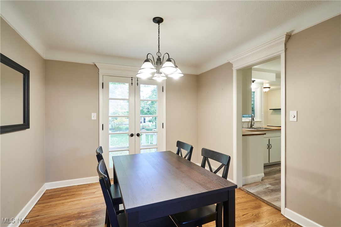1111 Ford Road Lyndhurst, OH 44124 - Photo 12 of 27 Dining space featuring french doors, light hardwood / wood-style flooring, sink, crown molding, and an inviting chandelier