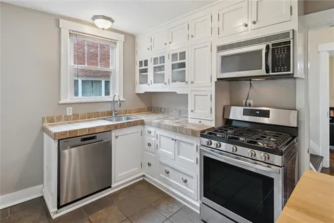 a kitchen with stainless steel appliances granite countertop white cabinets and window