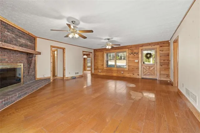 a view of an empty room with window and wooden floor