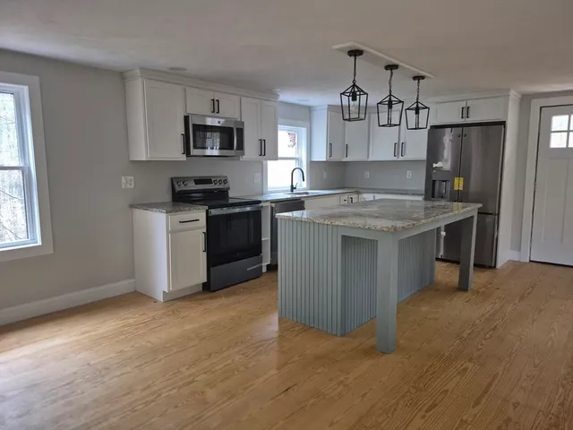 a kitchen with stainless steel appliances granite countertop a stove top oven a sink and a refrigerator