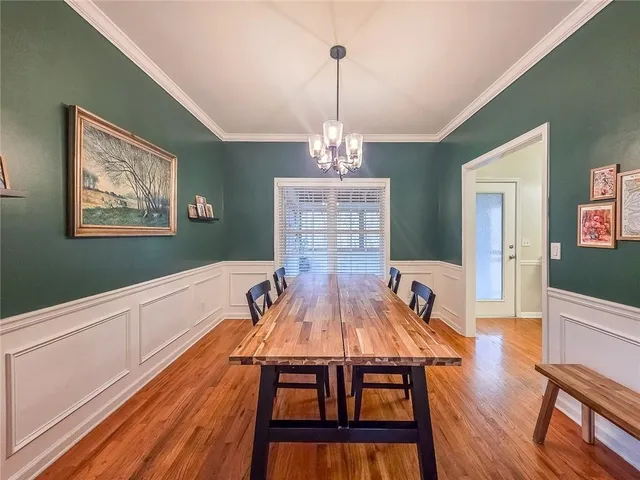a living room with furniture dining table wooden floor and a chandelier