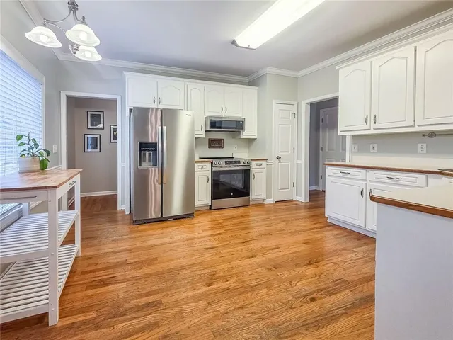 a kitchen with stainless steel appliances granite countertop a refrigerator oven stove a sink dishwasher and white cabinets with wooden floor