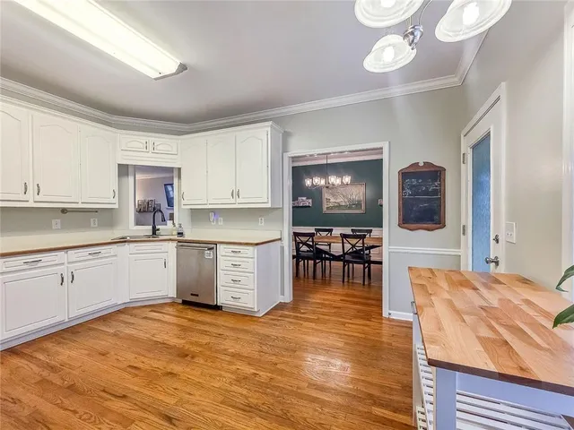 a kitchen with stainless steel appliances kitchen island granite countertop a stove a sink a dining table and chairs with wooden floor