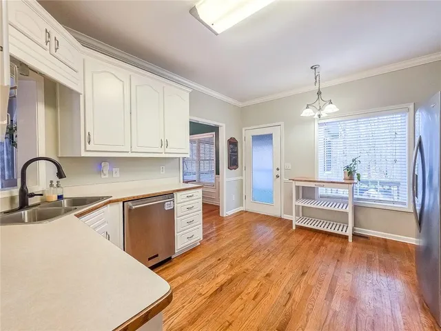 a kitchen with stainless steel appliances a stove top oven a sink dishwasher and a refrigerator with wooden floor