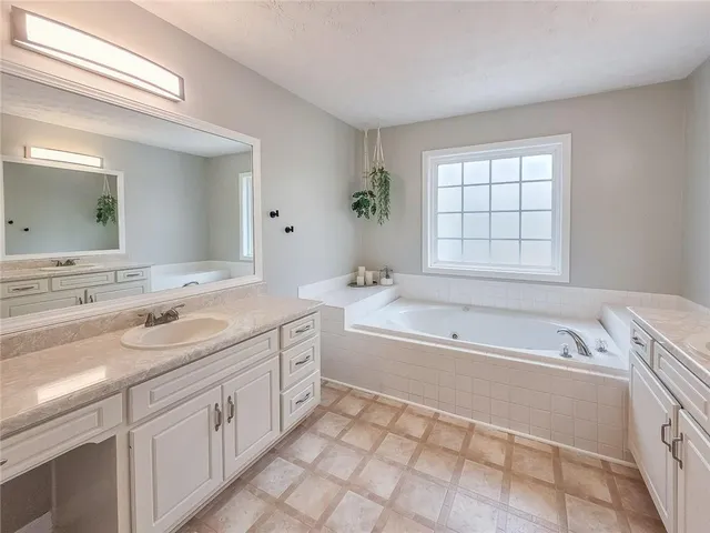 a spacious bathroom with a tub sink and mirror