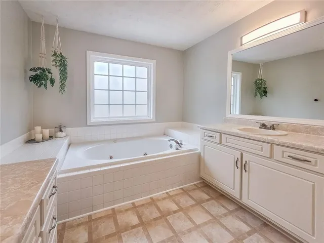 a spacious bathroom with a tub sink and mirror