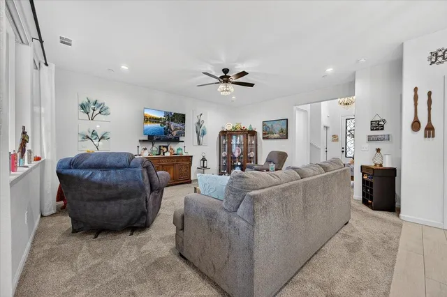 a living room with furniture kitchen view and a chandelier