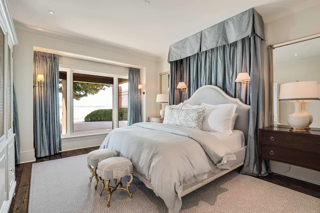 a bedroom with a bed lamps and a large window