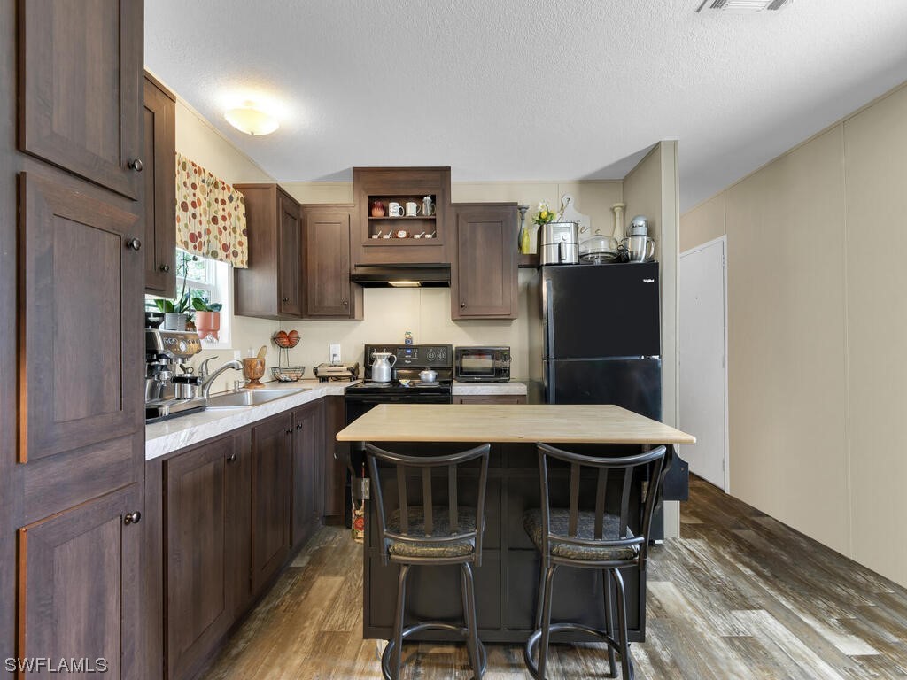 1183 Summerall Road LaBelle, FL 33935 - Photo 9 of 28 a kitchen with a table chairs refrigerator and sink