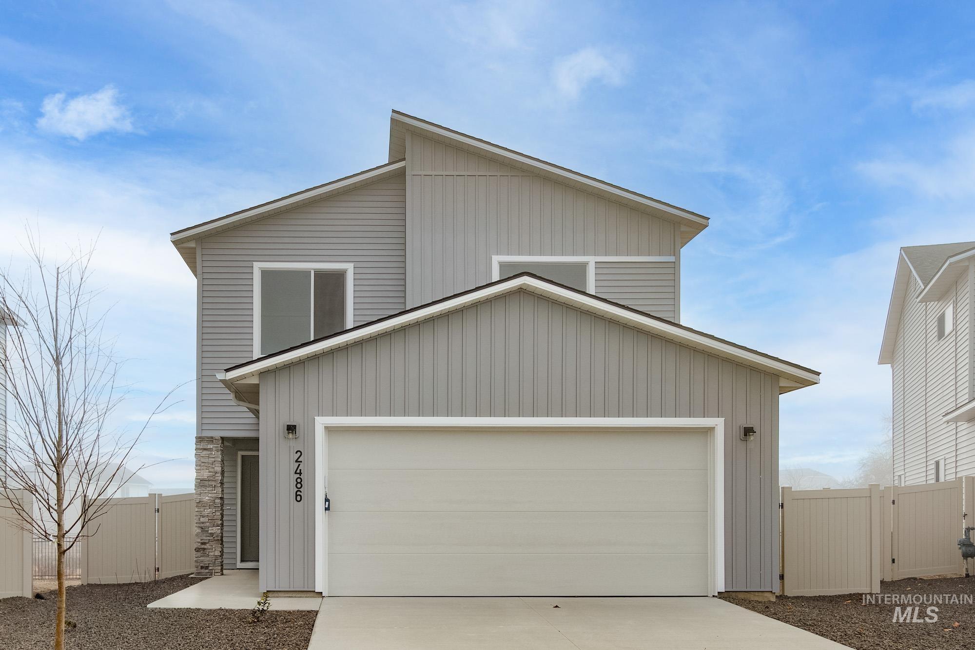 View of front of property with a gate, driveway, an attached garage, and stone siding