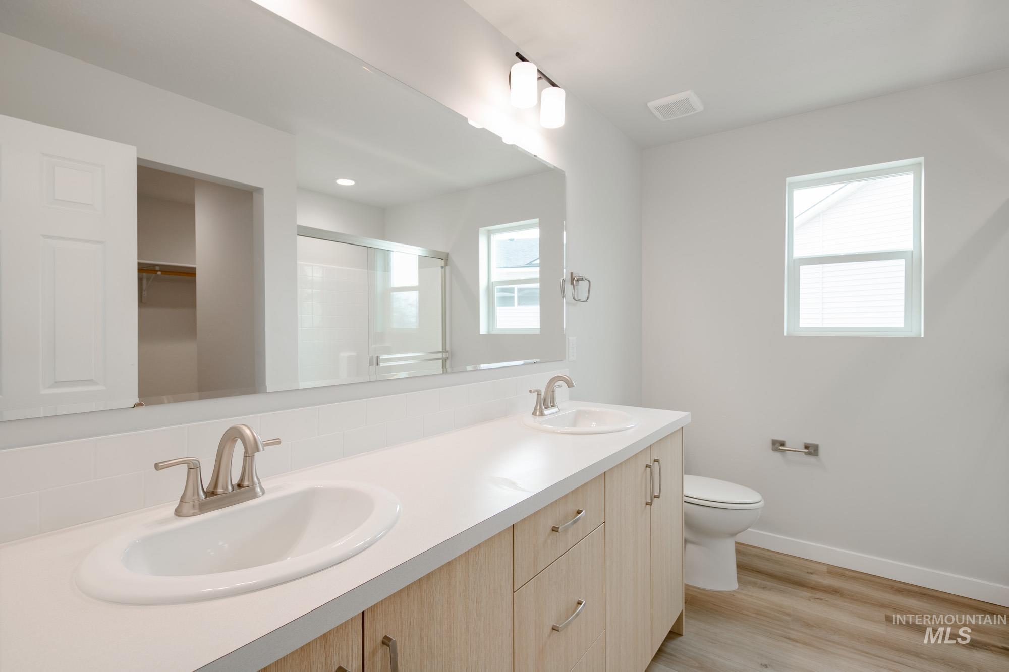 2486 West Fallon Loop Nampa, ID 83651 - Photo 13 of 18 Bathroom with double vanity, a stall shower, light wood-style flooring, and a walk in closet