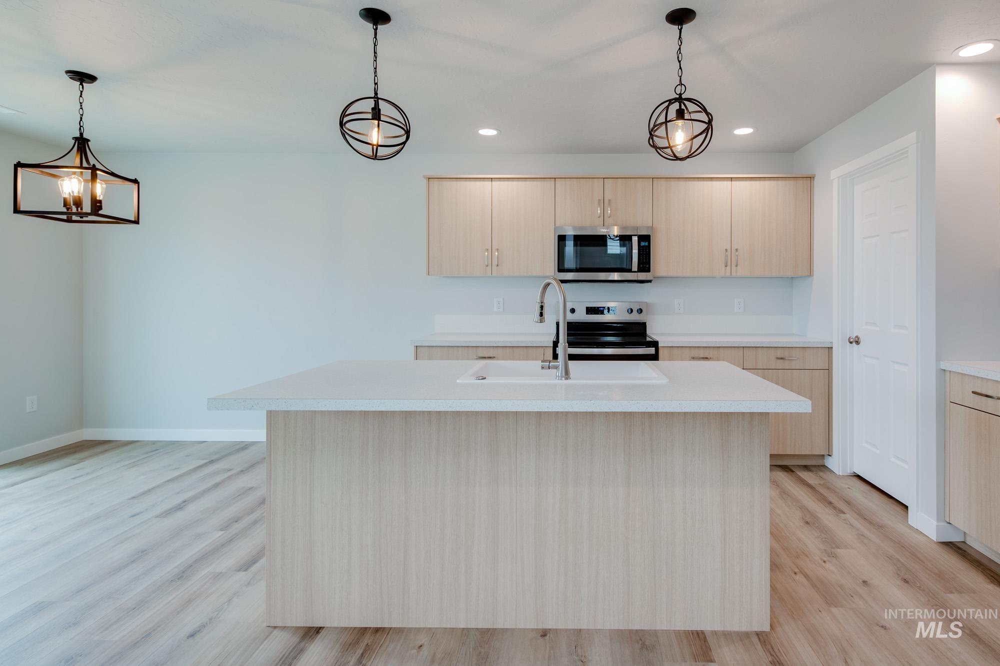 2486 West Fallon Loop Nampa, ID 83651 - Photo 3 of 18 Kitchen featuring light countertops, light brown cabinets, hanging light fixtures, light wood-style floors, and stainless steel appliances