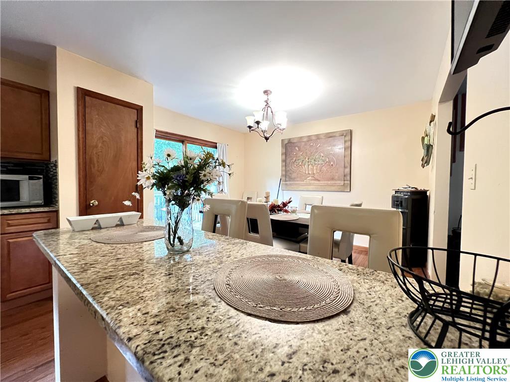 107 Warbler Court Bushkill, PA 18324 - Photo 17 of 32 a kitchen with a granite counter top a potted plant wooden floor and a chandelier