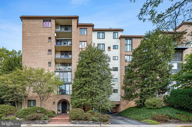 a front view of a residential apartment building with a yard and plants