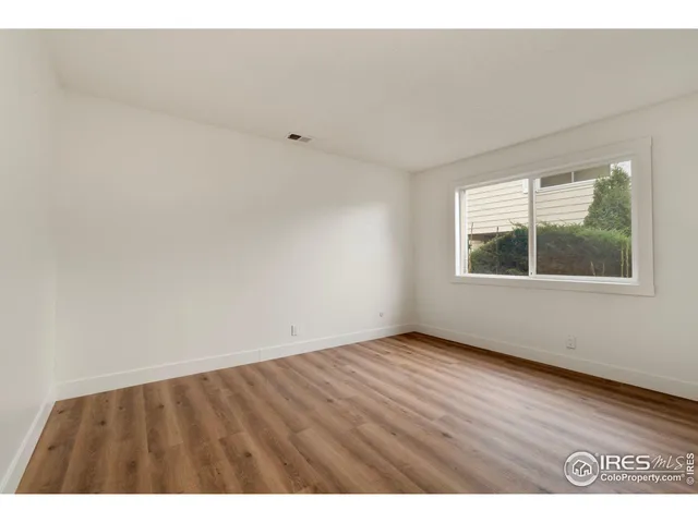 a view of an empty room with wooden floor and windows