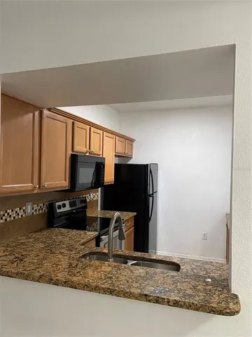 a kitchen with granite countertop a refrigerator and a stove top oven
