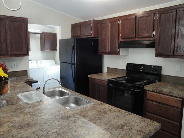 a kitchen with granite countertop a refrigerator stove and sink