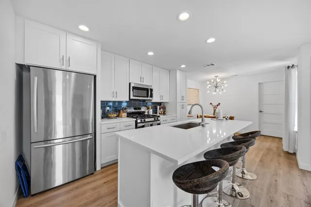 a kitchen with kitchen island a counter space a sink appliances and cabinets