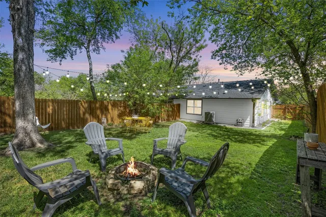 a view of a backyard with table and chairs potted plants and large tree