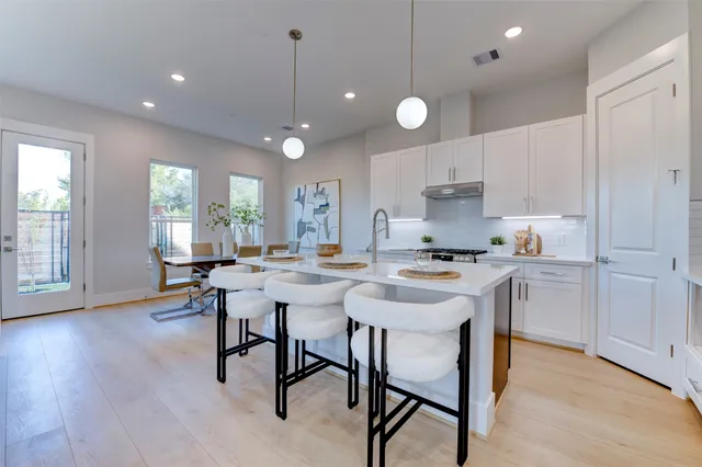 a kitchen with a dining table chairs and wooden floor