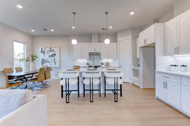 a open kitchen with kitchen island granite countertop a table and chairs in it
