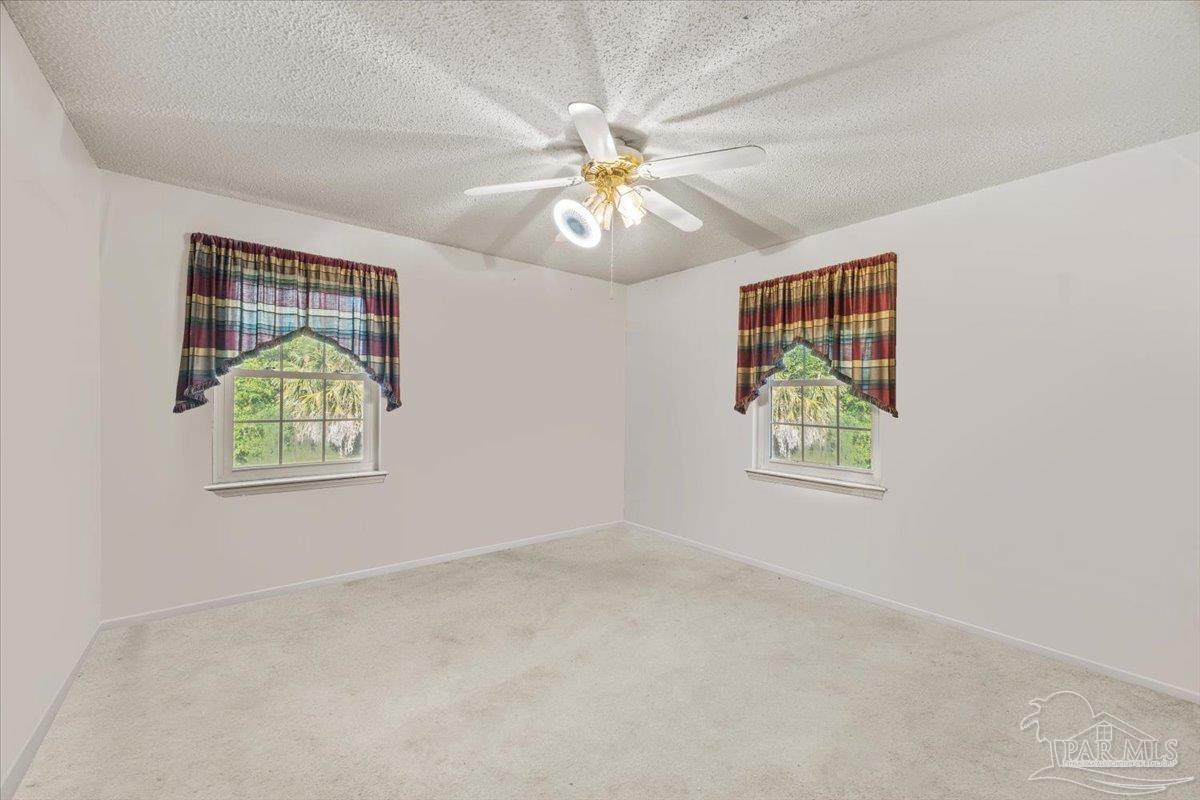 5560 Willard Norris Road Milton, FL 32570 - Photo 15 of 58 an empty room with windows and chandelier fan