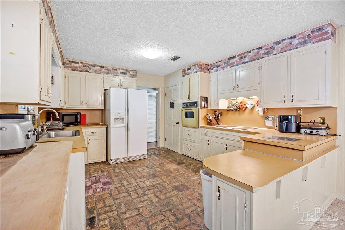 5560 Willard Norris Road Milton, FL 32570 - Photo 24 of 58 a kitchen with a refrigerator a stove and a sink with wooden floor