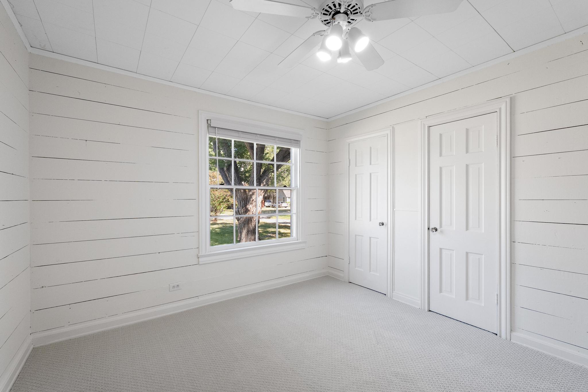 1707 Lexington Street Taylor, TX 76574 - Photo 19 of 29 Unfurnished bedroom featuring wood walls, multiple closets, carpet floors, and a ceiling fan