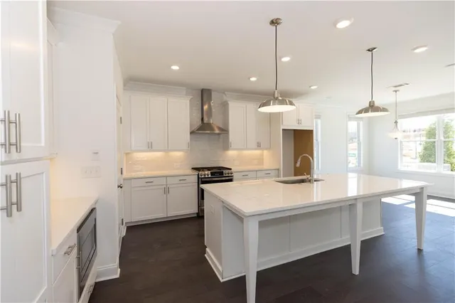 a kitchen with stainless steel appliances granite countertop a sink a stove a refrigerator and island with wooden floor