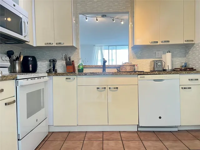 a kitchen with granite countertop white cabinets and white appliances
