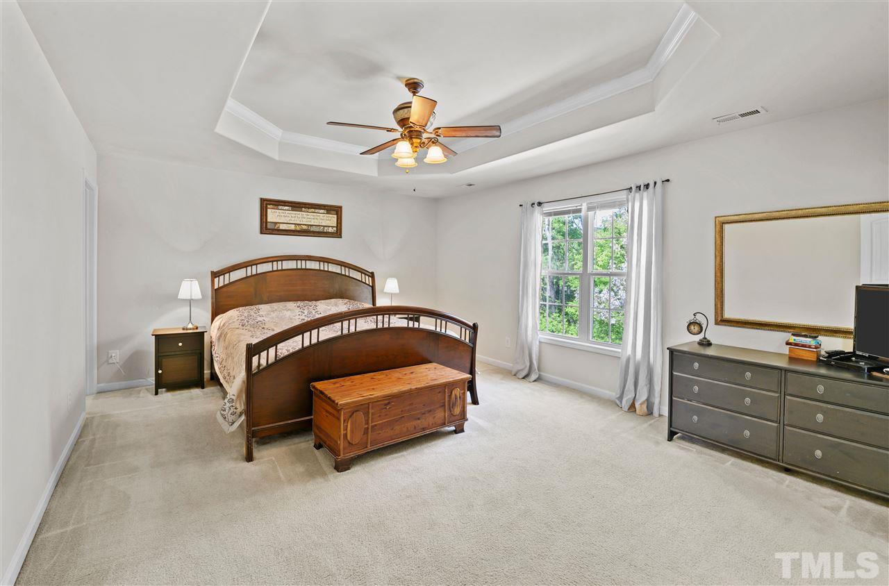 3239 Sunbright Lane Raleigh, NC 27610 - Photo 9 of 18 a spacious bedroom with a bed and a chandelier