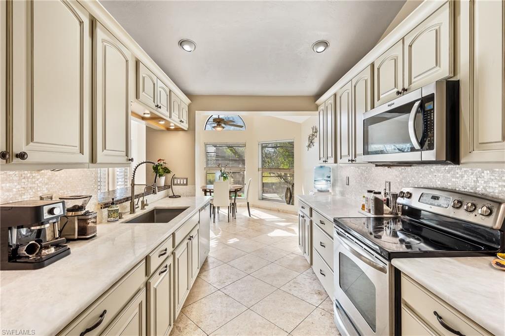 2271 Oakes Boulevard Naples, FL 34119 - Photo 13 of 47 a kitchen with stainless steel appliances a sink a stove and a refrigerator