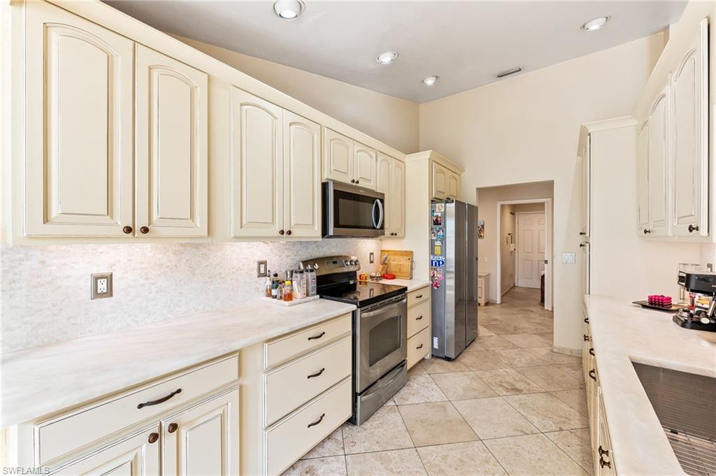 2271 Oakes Boulevard Naples, FL 34119 - Photo 14 of 47 a kitchen with granite countertop white cabinets and stainless steel appliances