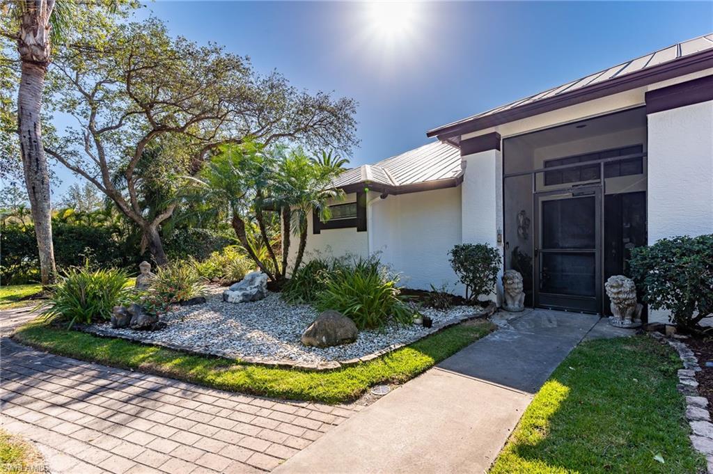 2271 Oakes Boulevard Naples, FL 34119 - Photo 3 of 47 a view of a white house with a yard potted plants and a large tree