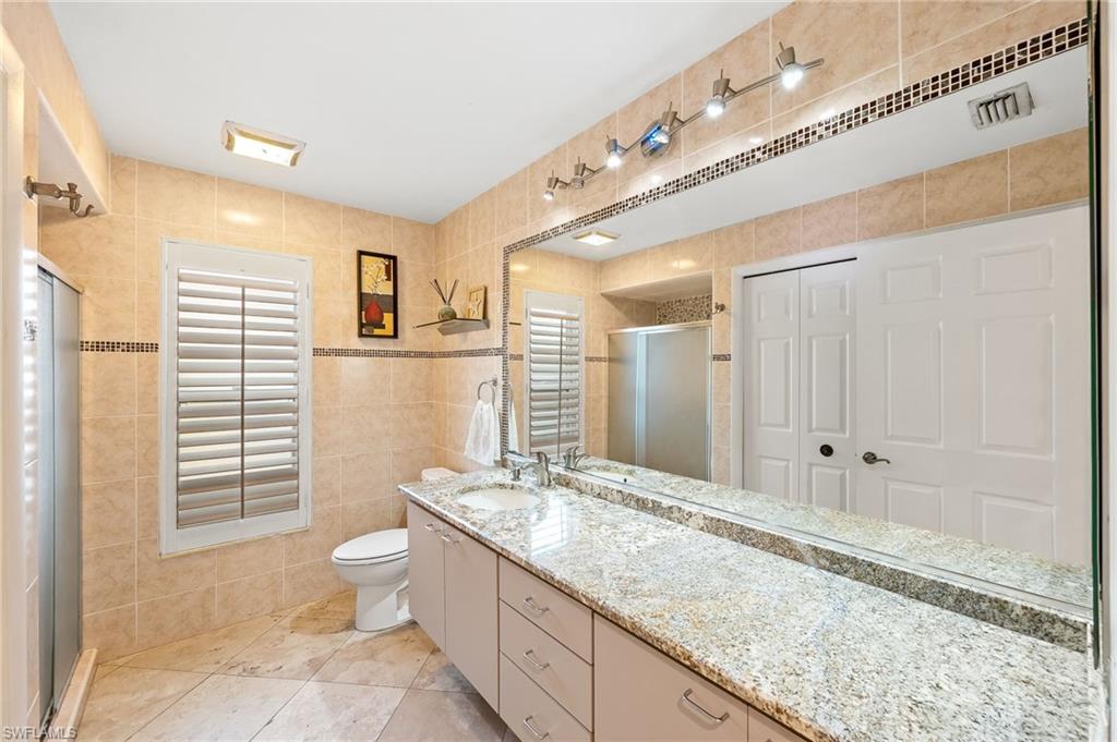 2271 Oakes Boulevard Naples, FL 34119 - Photo 31 of 47 a bathroom with a granite countertop double vanity sink a mirror and a shower
