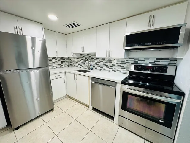 a kitchen with appliances a refrigerator and a stove top oven